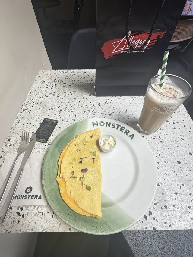 Omelette servido en un plato de Monstera con una bebida fría