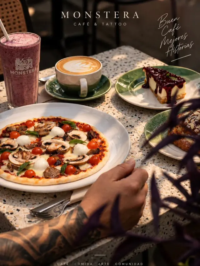 Pizza, capuccino, batido y cheesecake en una mesa de Monstera